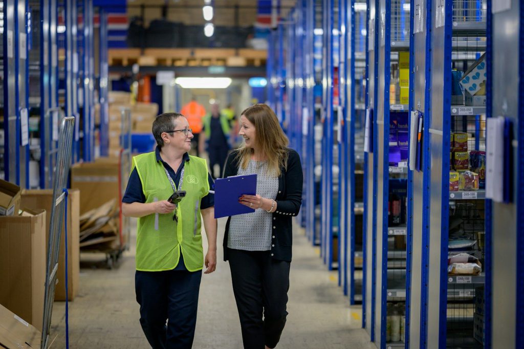 Two colleagues checking stock in a warehouse aisle